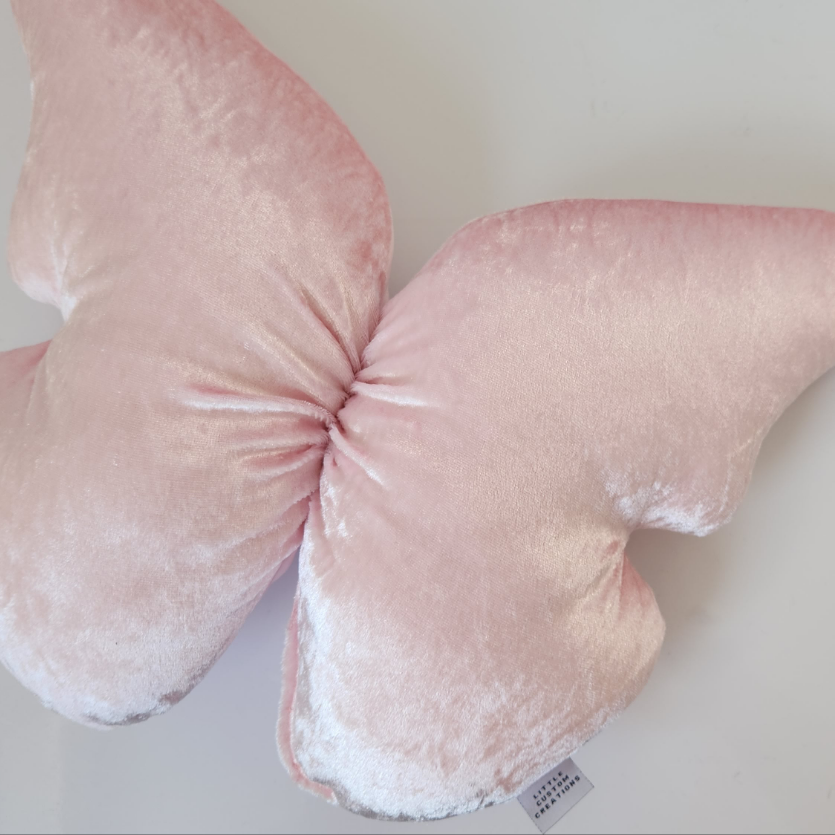Pink butterfly-shaped pillow on a light background