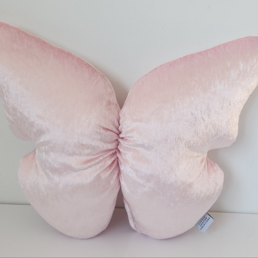 Pink butterfly-shaped pillow on a white background