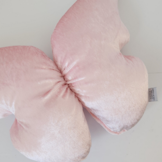 Pink baby pillow with a textured surface on a light gray background